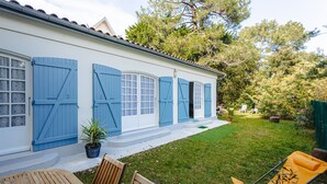 A house with blue shutters, a lawn, and outdoor furniture.
