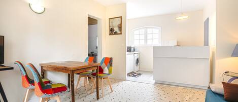 A compact living space with a dining area, kitchen, and a small seating area with a sofa and a round rug.