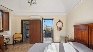 Ein Hotelzimmer mit Bett, Stuhl, Holzschrank, Spiegel und Balkonblick.