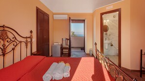 Ein Hotelzimmer mit Bett, einem Badezimmerspiegel, einem kleinen Tisch und einem Balkon mit Aussicht.