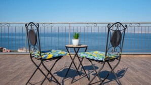 Ein Balkon mit zwei Stühlen, einem Tisch und einem Blumentopf.