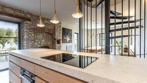 Eine moderne Küche mit Steinwand, Einbauofen und Pendelleuchten.