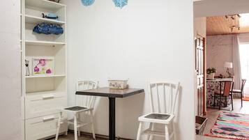 A room with a white cabinet, two chairs, a table, and a colorful rug.