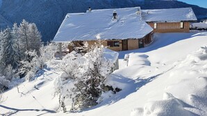 A snow-covered mountain landscape with a house featuring a sloped roof and a wooden exterior. - Apartment 'Chalet La Vourze' with Private Terrace, Balcony and Wi-Fi (QUEIGE)