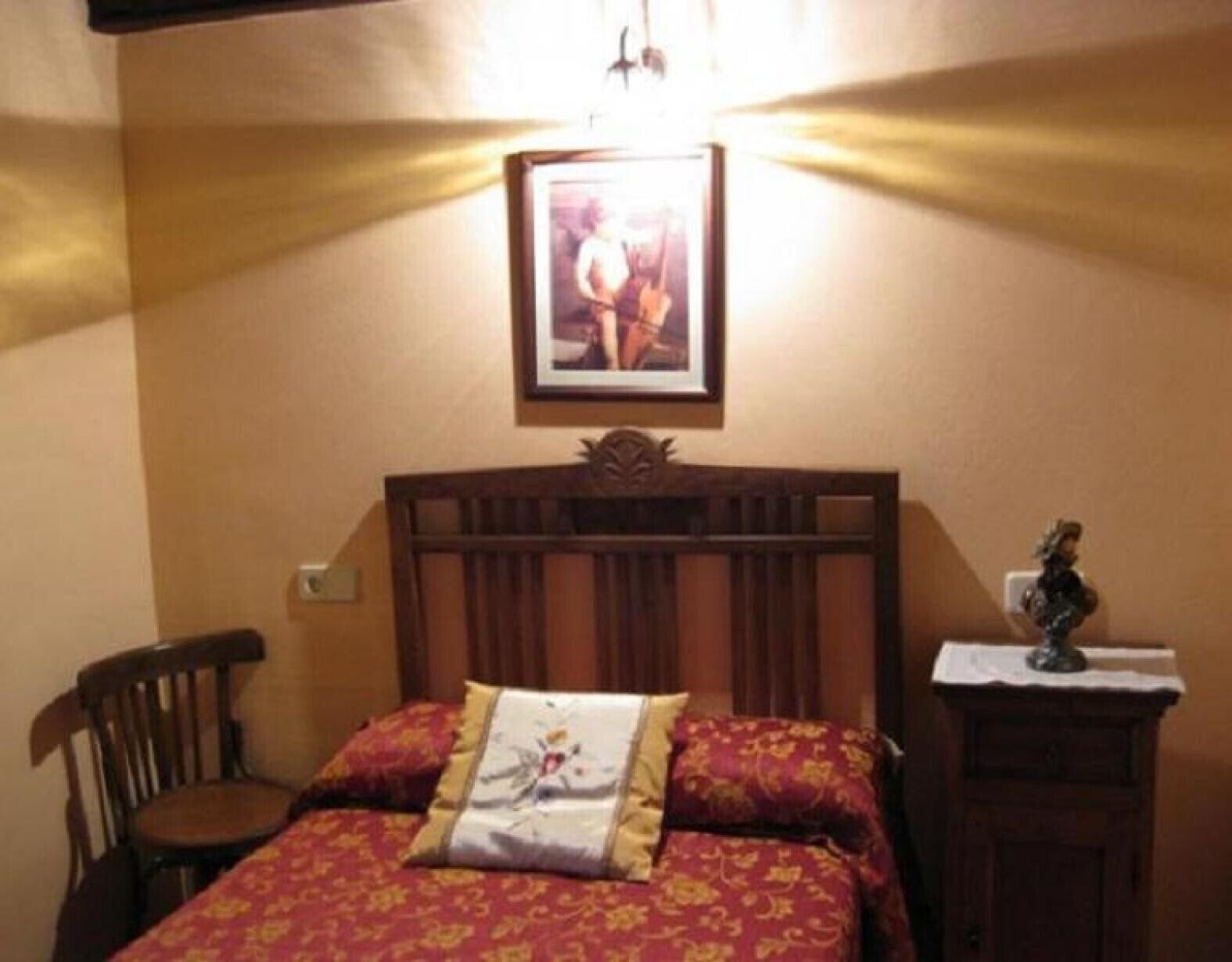 Une chambre à coucher avec un lit en bois, une table de chevet, une chaise et un tableau encadré au mur.