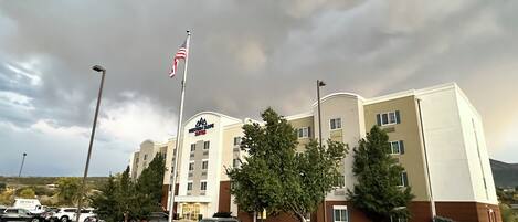 A Western Inn Suites hotel with a parking lot, flag, and surrounding trees.