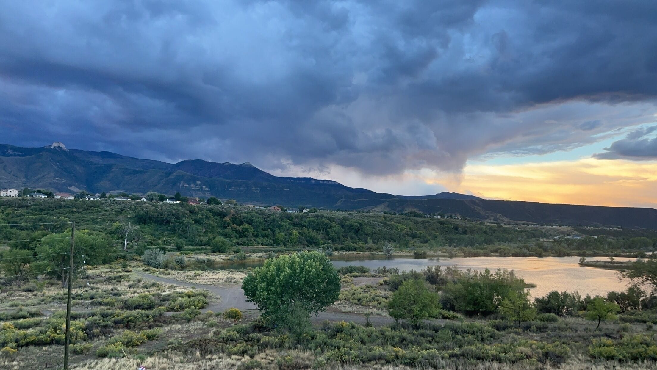 A landscape with a river, mountains, and a cloudy sky.