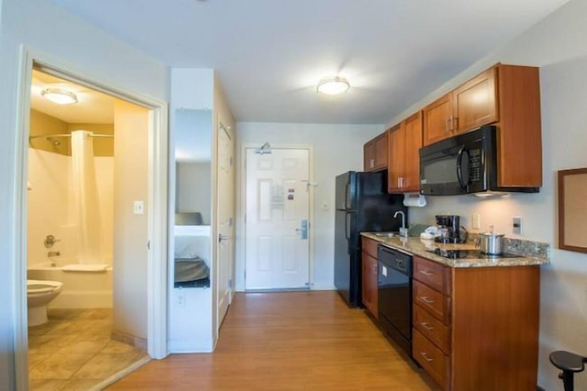 A compact kitchen with wooden cabinets, a microwave, and a dishwasher.