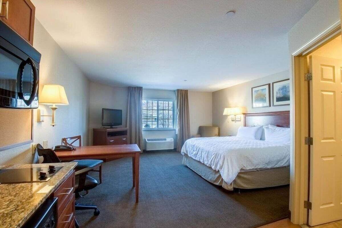 A hotel room with a bed, desk, television, and a window.
