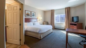 A hotel room with a bed, a desk, a television, and a window with curtains. - Western Slope suites (Parachute)
