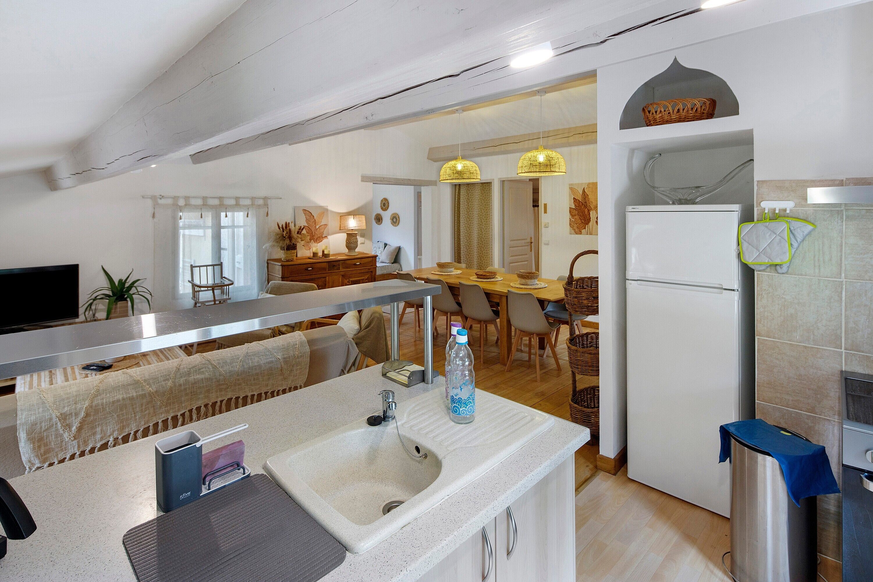 Une cuisine équipée d’un évier, d’un réfrigérateur et d’un coin repas avec des chaises et une table.
