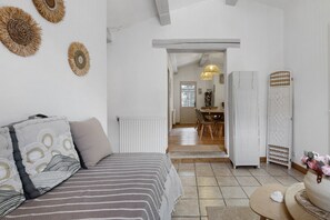 A bedroom with a bed, a dining area with chairs, a table, and a kitchen area with a refrigerator. - Independent Gîte at Mas De La Rode in the Forest with Private Outdoor Space and Parking (Saumane)