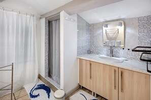 A bathroom with a shower, a sink, a mirror, and a tiled backsplash.