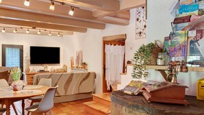 A cozy living room with a sofa, dining table, and TV. - Ground Floor Room 'Le Mont Aigoual' 15 m² (Saumane)