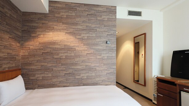 A hotel room with a bed, a wooden wall, a mirror, a television, and a small cabinet. - Tabist THE GREEN SAPPORO (Sapporo)