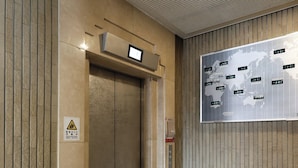 An elevator with a digital display, a safety warning sign, and a world map with time differences. - Tabist THE GREEN SAPPORO (Sapporo)