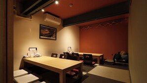 A room with a wooden table, chairs, a sofa, and a red wall. - Tabist THE GREEN SAPPORO (Sapporo)