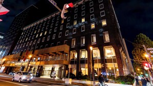 A multi-story hotel with a prominent entrance and a visible fire truck outside. - Tabist THE GREEN SAPPORO (Sapporo)