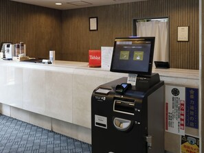 A hotel reception desk with a digital screen, a Tabist sign, a credit card reader, and a coin slot. - Tabist THE GREEN SAPPORO (Sapporo)