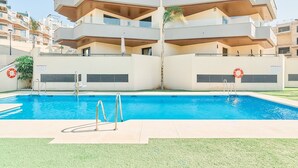 A swimming pool with two ladders, surrounded by a building with multiple balconies and a palm tree. - Apartment 'Bc01 El Sueño Marinsa Beach 2' with Sea View, Wi-Fi and Air Conditioning (El Morche)
