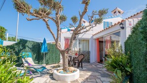 A patio with lounge chairs, a tree, and a dining area with chairs and a table. - Holiday Home “Vistamar 2” with Sea View, Terrace and Wi-Fi (Vinarós)