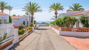 A narrow street with white houses, palm trees, and a view of the sea. - Holiday Home “Vistamar 2” with Sea View, Terrace and Wi-Fi (Vinarós)