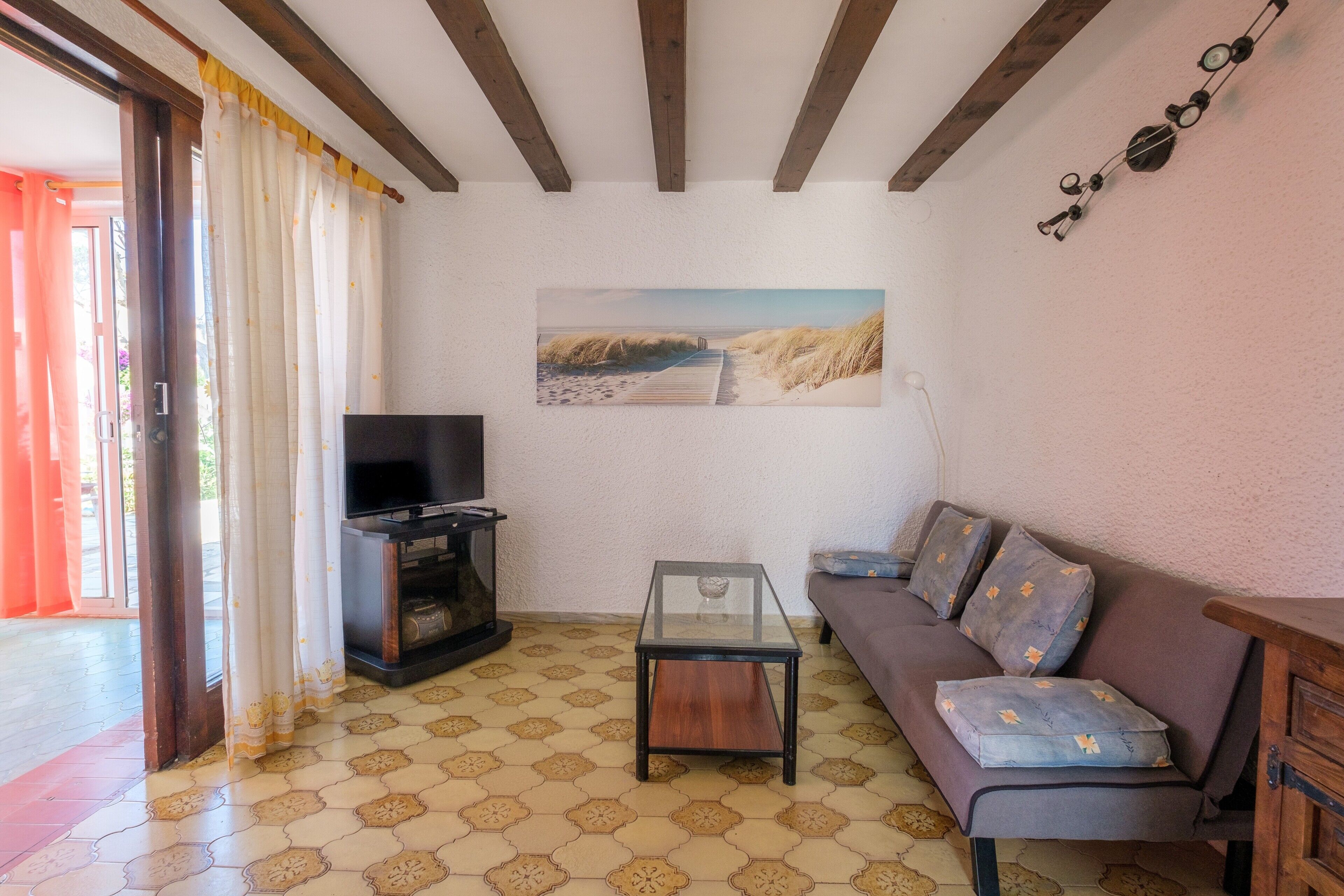 Un soggiorno con un divano, un tavolino in vetro, una televisione e un quadro appeso al muro.