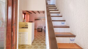 A staircase with wooden steps and blue decorative tiles, leading to a kitchen area with a tiled floor and a small table. - Holiday Home “Vistamar 2” with Sea View, Terrace and Wi-Fi (Vinarós)