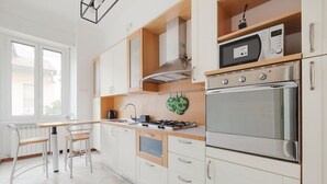 A modern kitchen with white cabinets, a gas stove, an oven, and a microwave. - GuestHost - Gambara M1 White Functional Appt x4 (Milano)