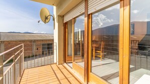 Een balkon met een schotelantenne, grote schuifdeuren en een uitzicht op een gebouw op de achtergrond.