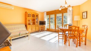 Een kamer met een bank, televisie, eettafel, stoelen en een kast.