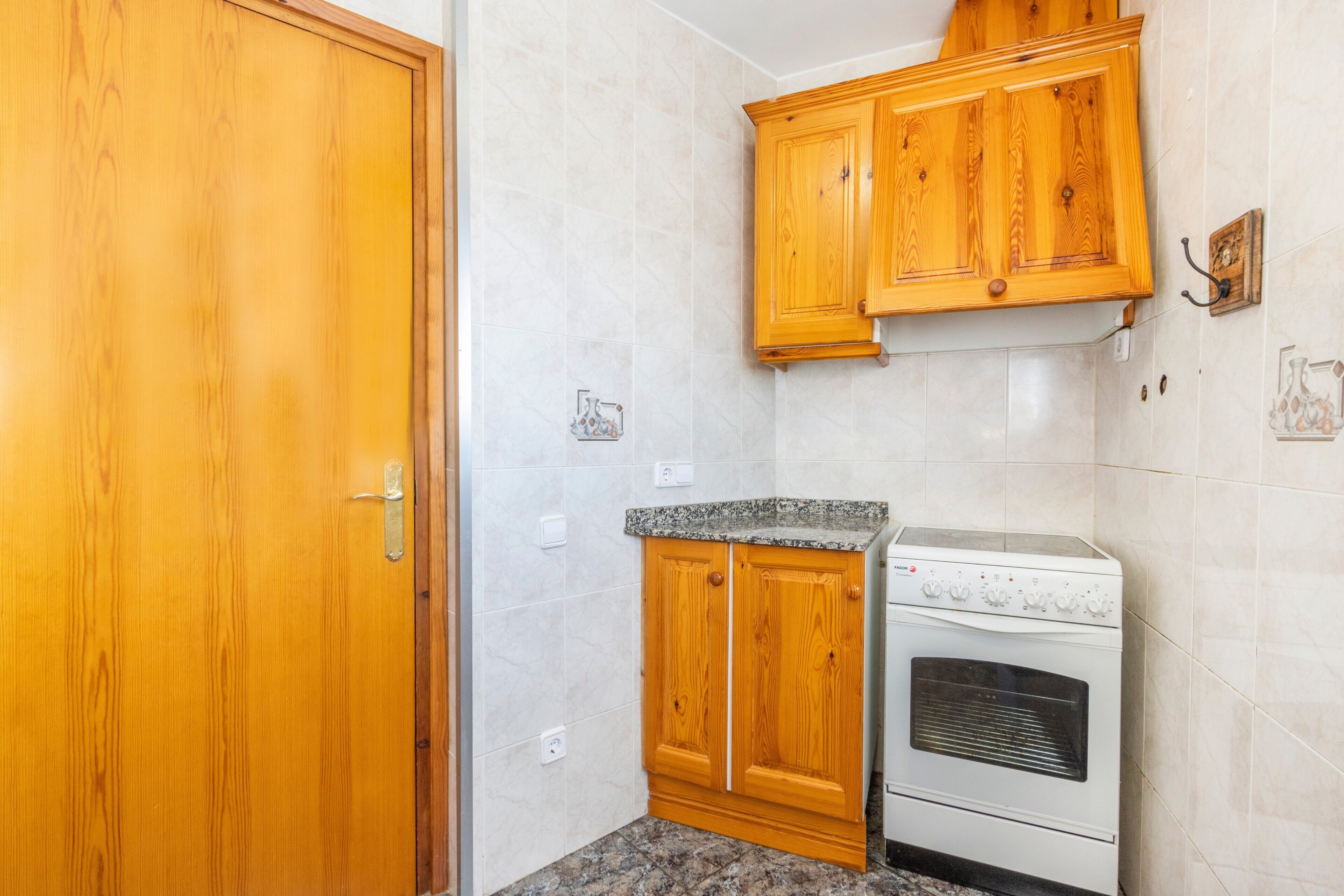 A kitchen with wooden cabinets, a built-in oven, and a granite countertop.