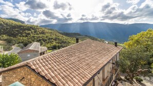 A building with a tiled roof, stone walls, and a view of mountains.