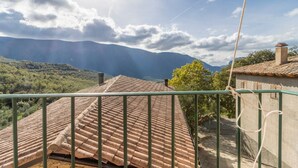 A terrace with a tiled roof, a metal railing, and a view of distant mountains.