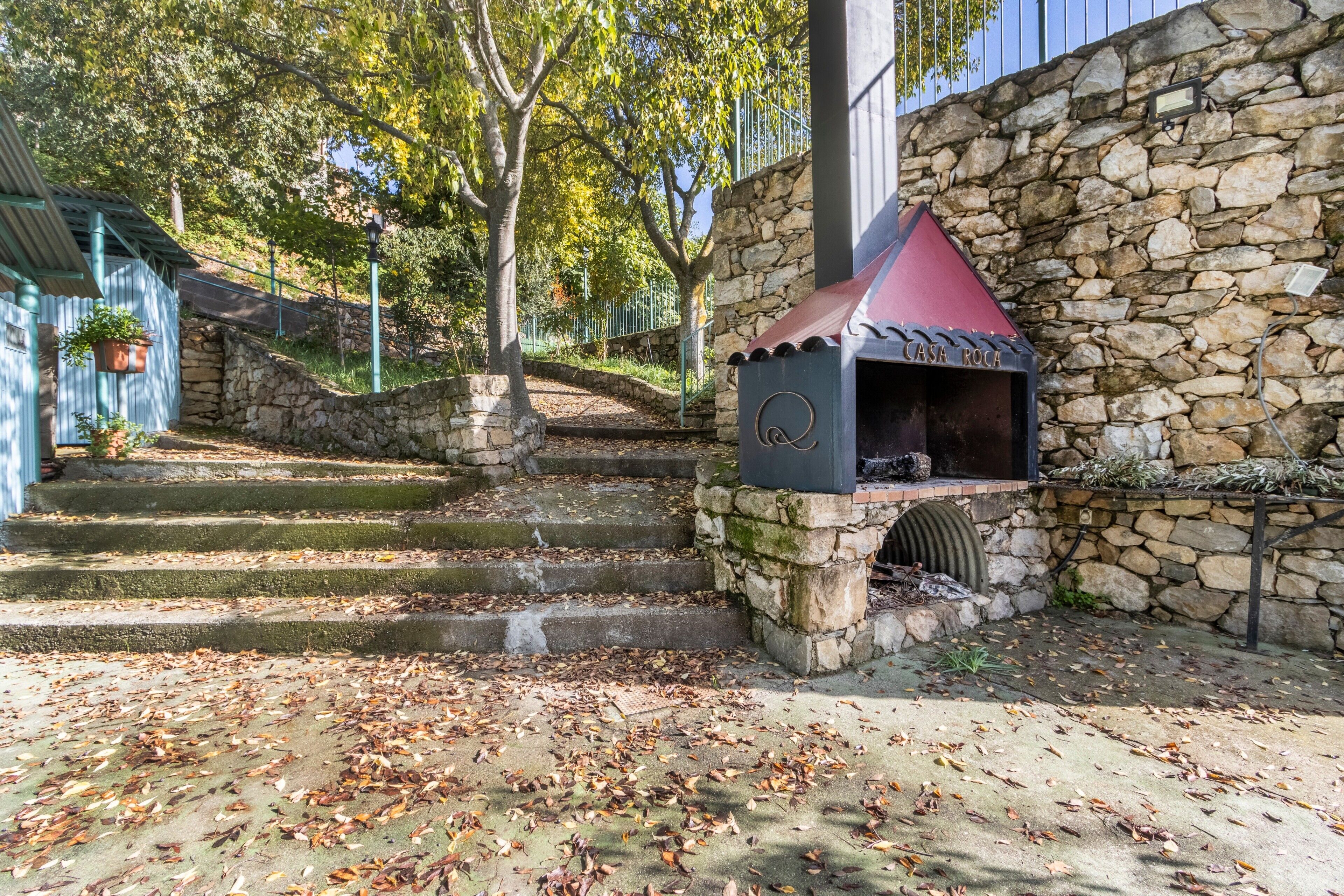 A stone building with a barbecue area, steps leading up to it, and a stone wall.