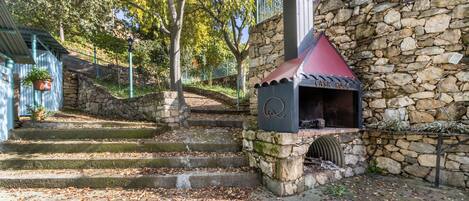 A stone building with a barbecue area, steps leading up to it, and a stone wall.