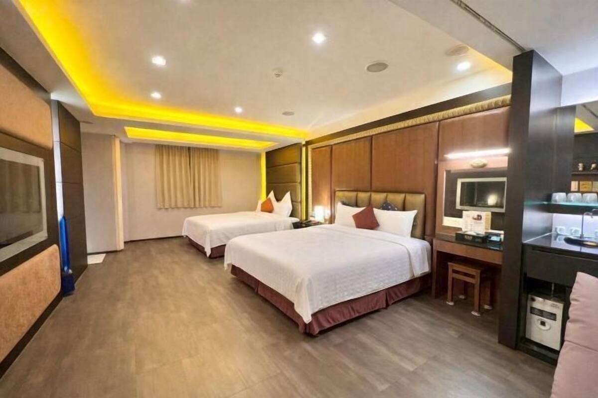 A hotel room with two beds, a desk, a television, and a minibar.
