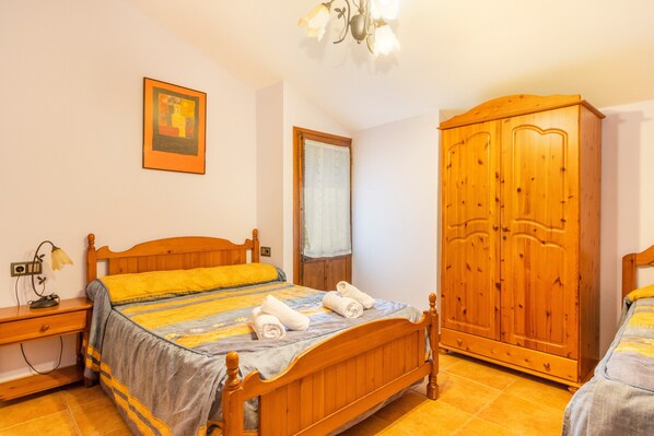 Une chambre à coucher avec un lit en bois, une armoire, une table de chevet et un tableau accroché au mur.