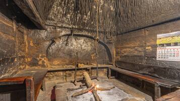 Un interior de piedra con una chimenea, bancos de madera y un calendario en la pared.