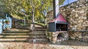 A stone building with a barbecue area, steps leading up to it, and a stone wall.
