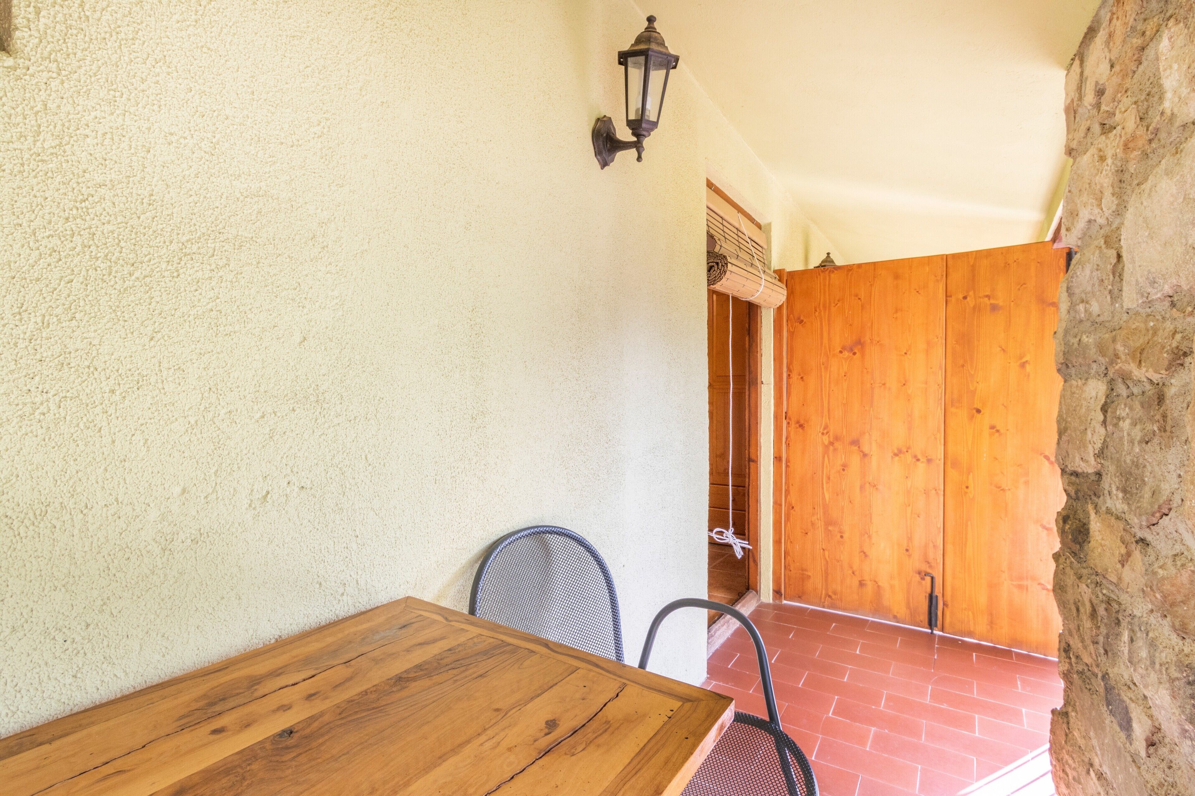 A wooden table and chairs in a room with a textured wall and a stone wall.