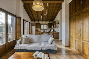 A cozy living room with a sofa, wooden cabinets, and a view through large windows.