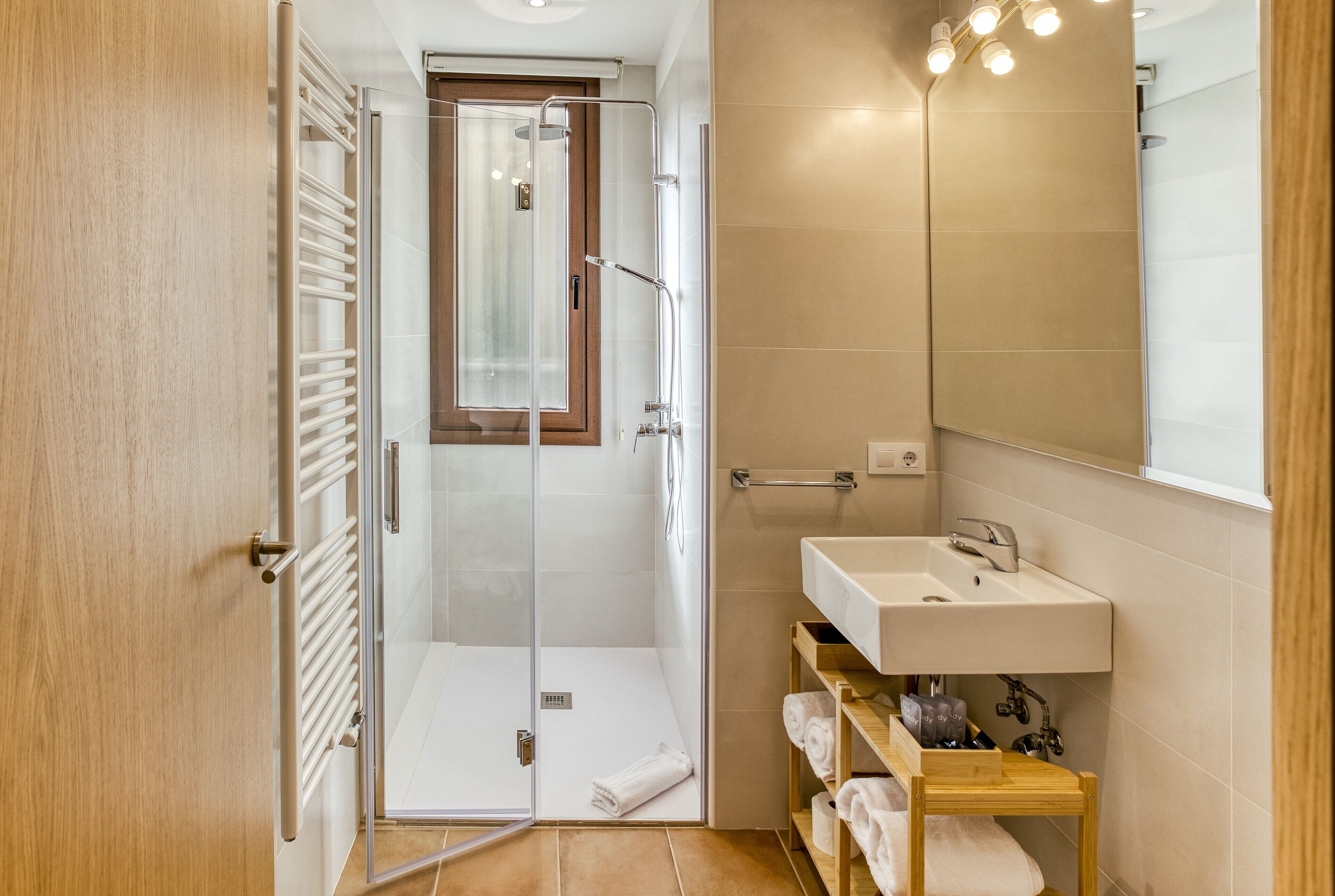 A modern bathroom with a glass-enclosed shower, a wooden vanity with a sink, and a mirror.