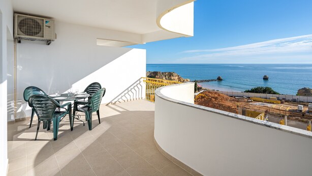 Un balcon avec une table et des chaises, une vue sur la mer et un chantier de construction.