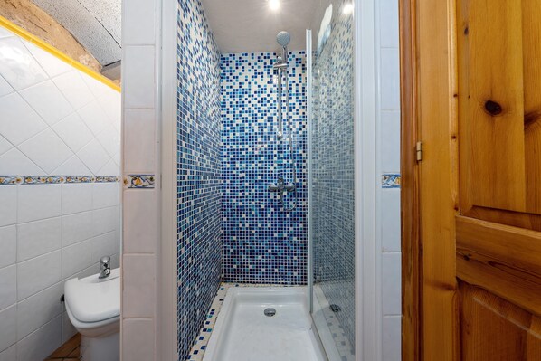 Une salle de bain avec une douche, des carreaux blancs, un lavabo et une porte en bois.