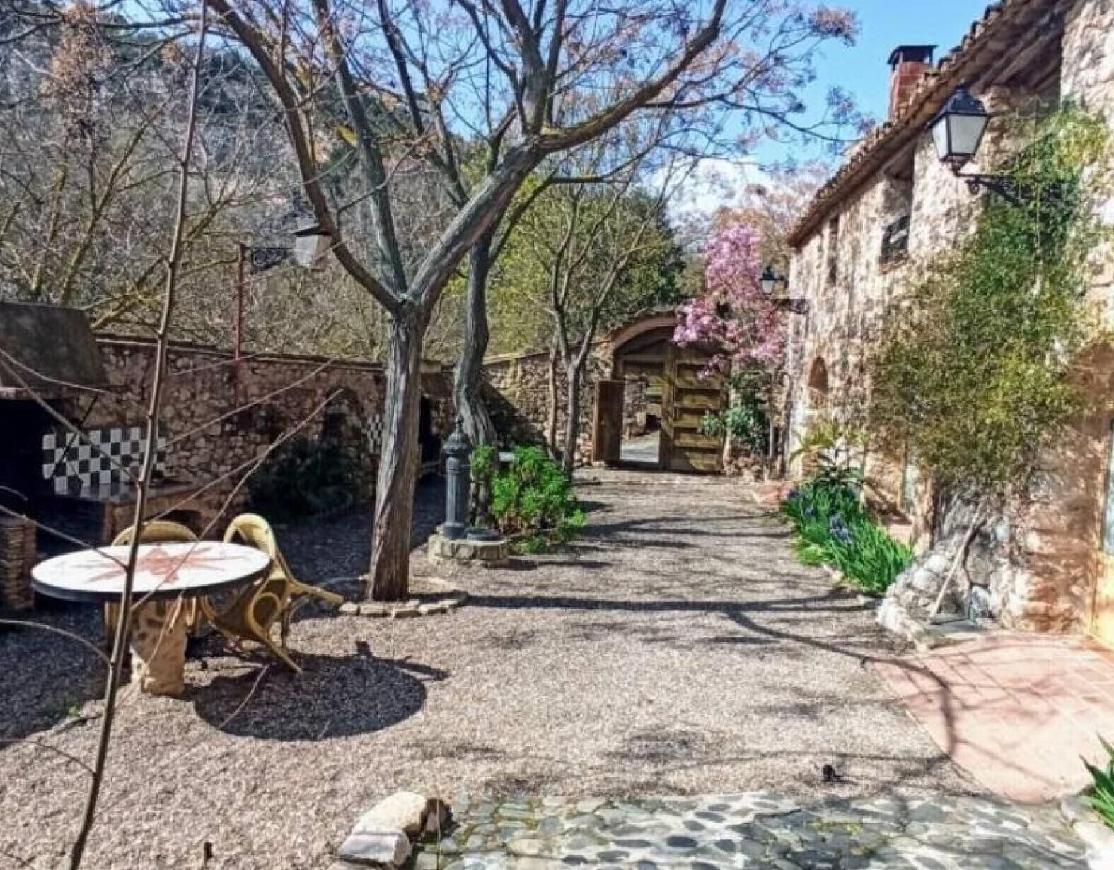 A courtyard with a gravel path, a wooden gate, and a stone wall.