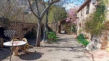 A courtyard with a gravel path, a wooden gate, and a stone wall.