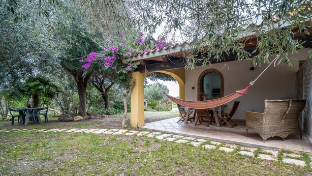 Un espace extérieur abrité, aménagé avec un hamac, une table et des chaises.