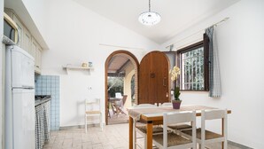 Une cuisine avec un coin repas, une porte en bois et une fenêtre avec des rideaux.