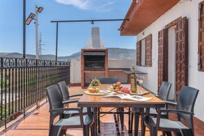 Eine Terrass mit Essplatz, Grill und Blick auf die Hügel.